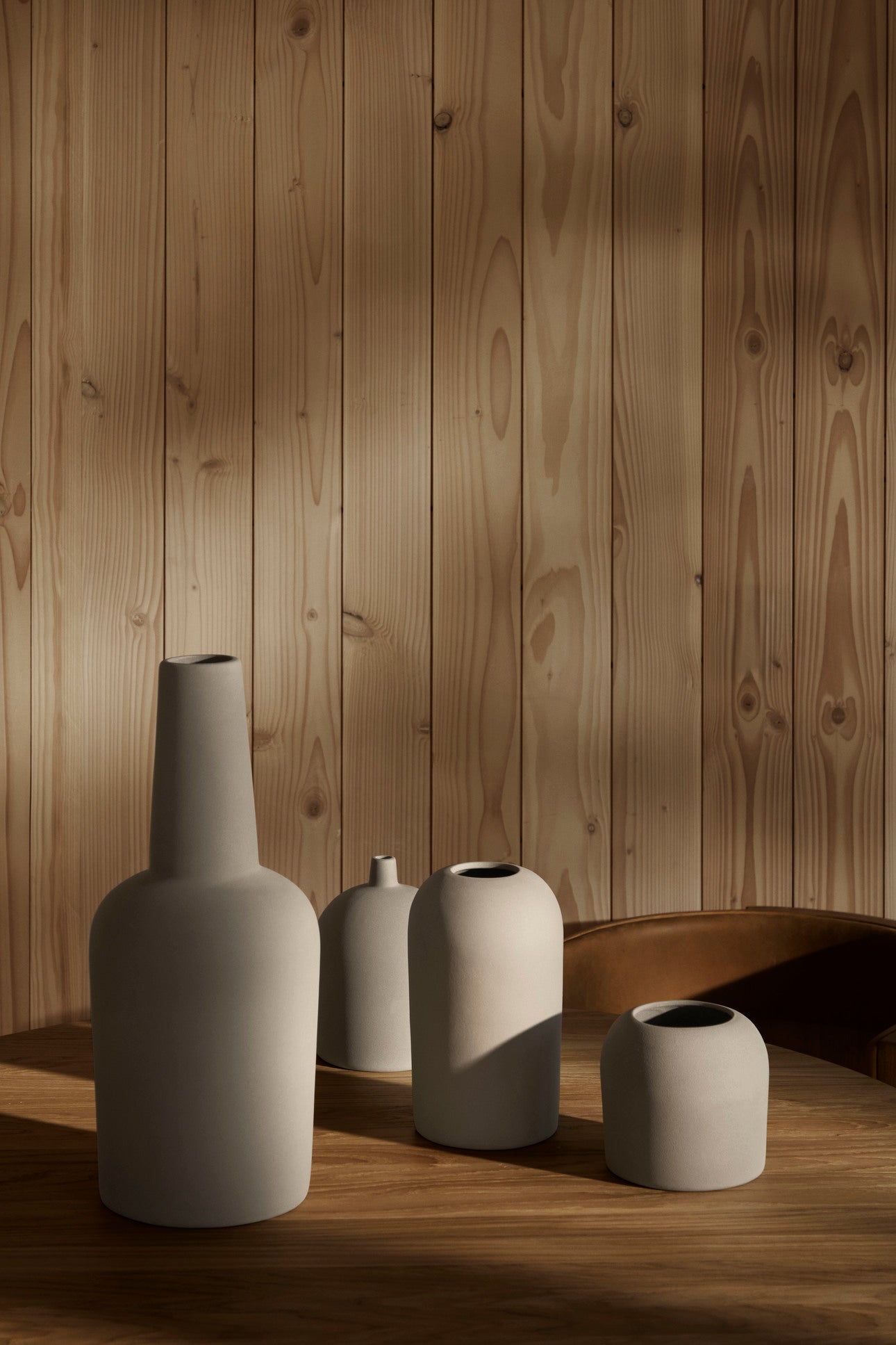 Set of four ceramic vases on a wooden surface with a wooden panel background